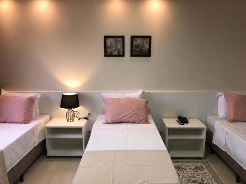 阿拉瓜伊纳Baruch Hotel的客房设有两张带粉红色枕头和桌子的床。