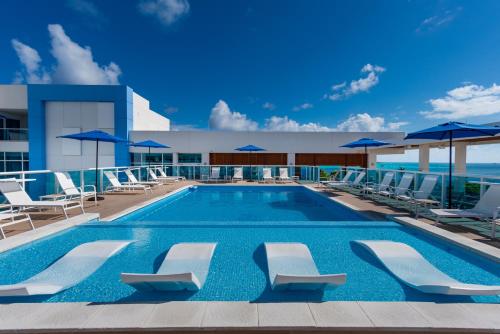 圣安德烈斯Aquamare Hotel的一座大楼内的游泳池,配有椅子和遮阳伞