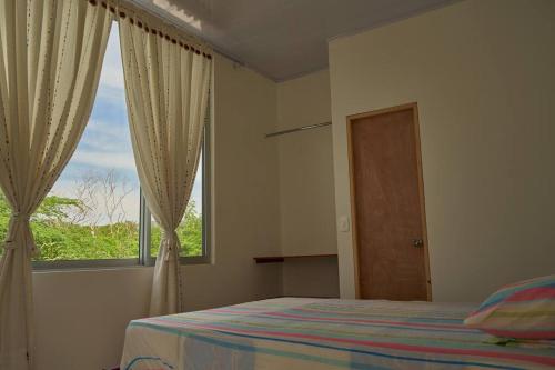 吉拉尔多特Casa vacacional Girardot 5 habit的一间卧室设有一张床和一个大窗户