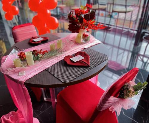 Batu MerahGolden Palace Hotel的一张桌子、红色的椅子和一张粉红色的桌子,上面有鲜花