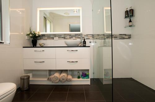 奥尔巴尼Kinsellas Water Views的一间带水槽、卫生间和镜子的浴室