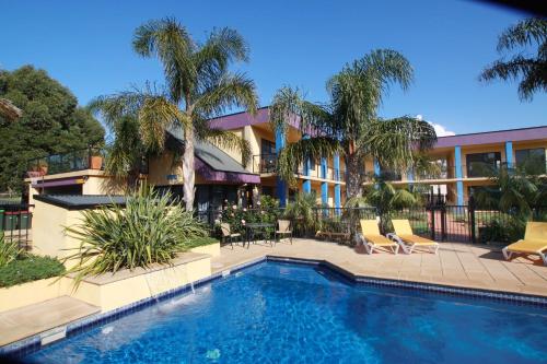 梅林布拉梅林布拉鹦鹉螺公寓式酒店的棕榈树建筑前的游泳池