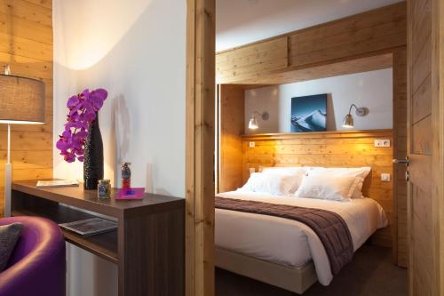 里蒙纽耶雷斯当斯夏雷瓦隆峰酒店的一间卧室配有一张大床和木制床头板