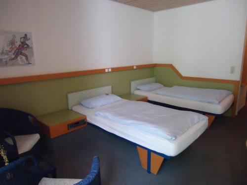 埃根斯泰因-列奥波德港尤尔根·法斯宾德运动酒店的配有椅子的客房内的两张单人床