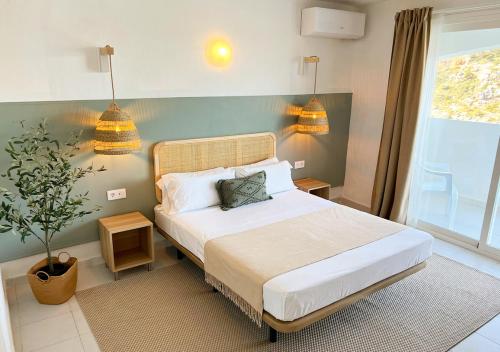 卡拉恩波特Club Menorca - Solo Adultos的一间卧室,配有一张带两盏灯和一根植物的床