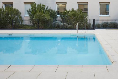 波尔多波尔多罗德萨阿德吉奥公寓式酒店的大楼前的大型蓝色游泳池