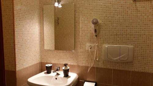 罗马莫赛克旅馆的一间带水槽和镜子的浴室以及一部电话