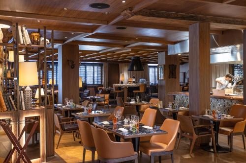 采尔马特Schweizerhof Zermatt - a Small Luxury Hotel的餐厅设有桌椅,厨师为背景