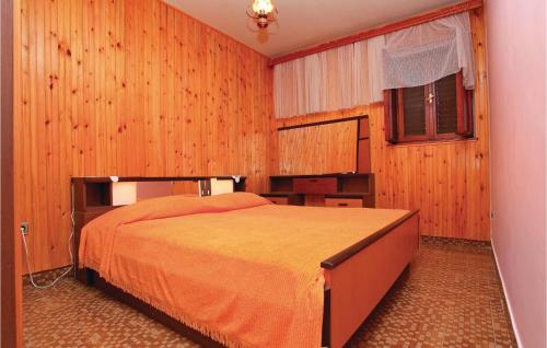 布拉托Cozy Home In Blato With House Sea View的一间卧室配有一张带木墙和窗户的床。
