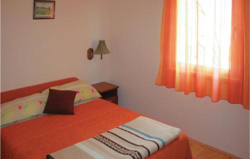 Bosiljevo2 Bedroom Cozy Home In Bosiljevo的一间卧室配有一张带橙色毯子和窗户的床。
