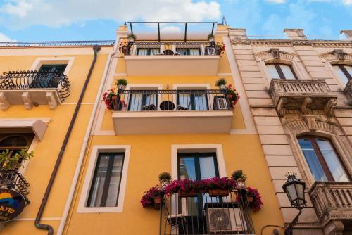 陶尔米纳瓦伦蒂娜旅馆的一座黄色的建筑,设有阳台,鲜花盛开