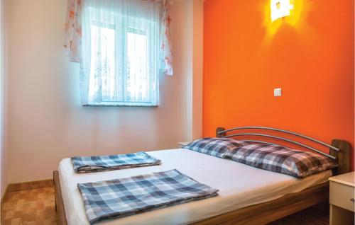 马卡尔斯卡Cozy Apartment In Makarska With Kitchen的一间卧室拥有橙色的墙壁,配有一张带两个枕头的床