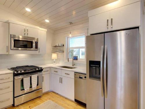 费尔霍普Downtown Fairhope Cottage的厨房配有白色橱柜和不锈钢冰箱