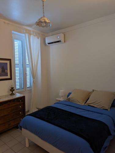 马赛le Cocooning Marseillais的一间卧室设有蓝色的床和窗户。