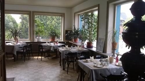 克雷姆林根温伯格酒店的餐厅设有白色的桌椅和窗户。