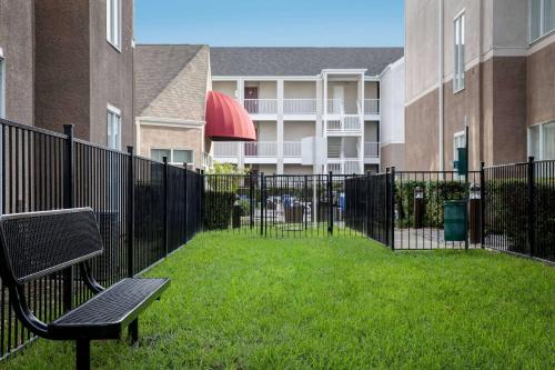 达拉斯Sonesta ES Suites Dallas Medical Market Center的围栏旁的公园长凳,有建筑物