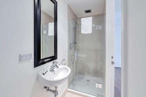 奥克兰THE VIADUCT WATERFRONT LUXURY - Views & Location!的浴室配有盥洗盆和带镜子的淋浴