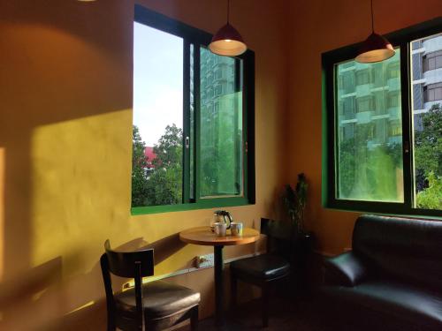 佛山Foshan Cuba Youth Hostel的一个带两扇窗户的房间,配有一张小桌子和椅子