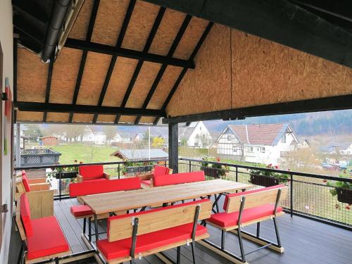 哈伦贝格Chic Holiday Home in Liesen with Garden的一个带木桌和红色椅子的大甲板