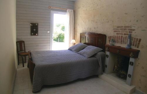 La Jonchère拉容谢勒2号度假屋的一间卧室设有一张带壁炉和窗户的床。
