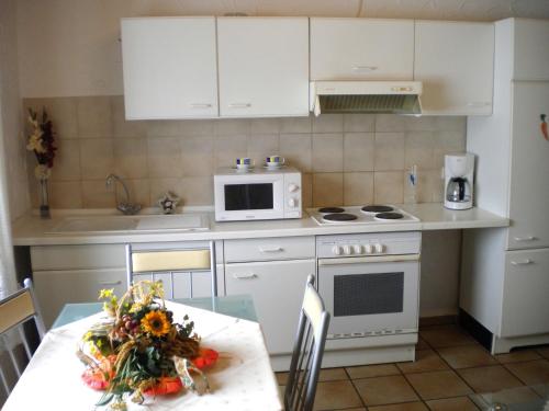 阿滕多恩Attractive Apartment in Silbecke with Garden的厨房配有白色橱柜、桌子和微波炉