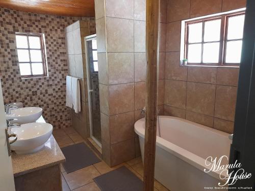 哈博罗内Moritshane estate的一间带两个盥洗盆、浴缸和卫生间的浴室