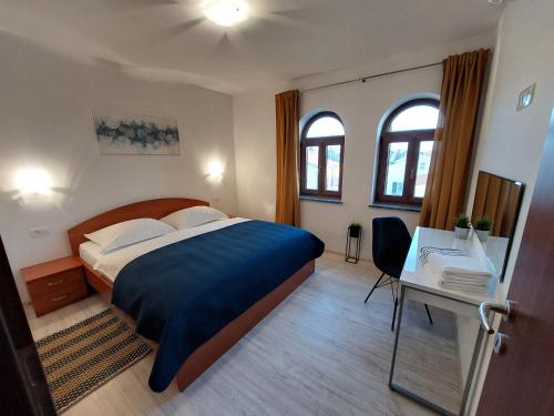巴尔巴特纳拉布Apartments Amfora的一间卧室配有一张床、一张书桌和两个窗户。