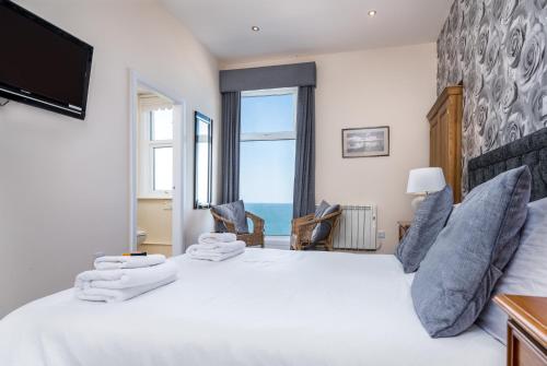 惠特比Riviera Guesthouse的卧室设有一张大白色的床和大窗户