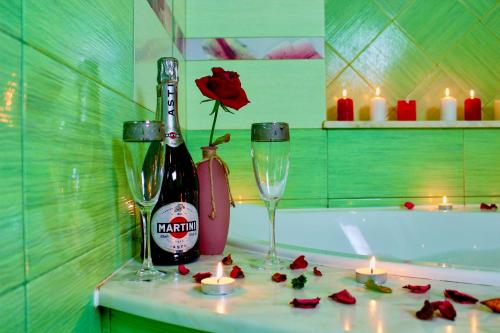索契Sunlion Баунти Hotel的浴室提供一瓶葡萄酒、两杯酒和蜡烛