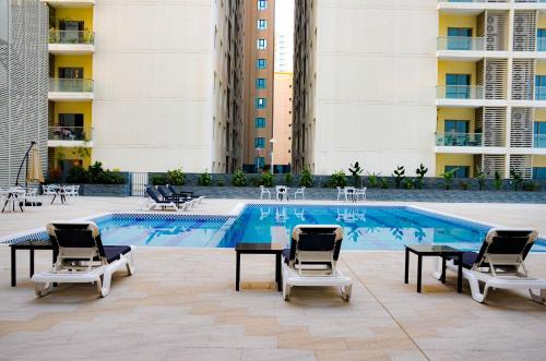 朱菲尔JUFFAIR BOULEVARD HOTEL & SUITES的一个带桌椅的游泳池和一个游泳池
