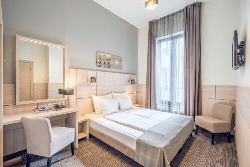 里加Wellton Centrum Hotel & SPA的酒店客房带一张床、一张书桌和一面镜子