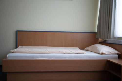 卡尔斯特RadlStadl - Brauhaus und Hotel的一张带木制床头板和白色床单的床