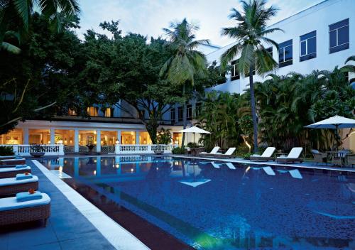 钦奈Taj Connemara, Chennai的酒店游泳池设有椅子,酒店大楼