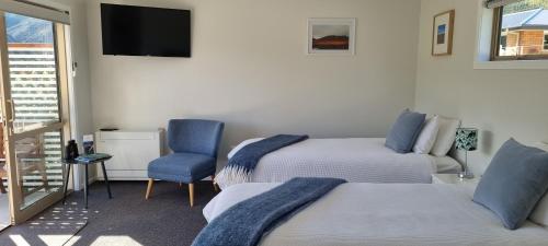 克伦威尔Lodges on Pearson - Unit 2的客房设有两张床、一台电视和一把椅子。