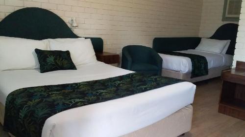 WarrenMacquarie Valley Motor Inn的酒店客房,配有两张床和椅子