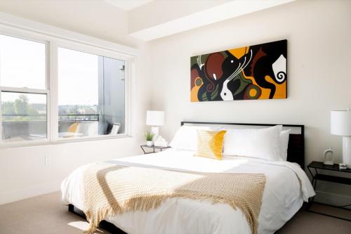 丹佛City views - Luxe Loft - Zuni Lofts的白色卧室配有一张床,墙上挂着一幅画