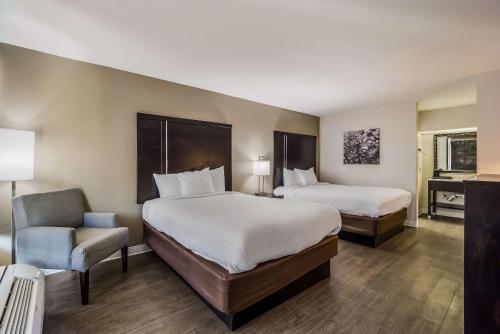 佛罗伦萨Clarion Inn & Suites的酒店客房,配有两张床和椅子