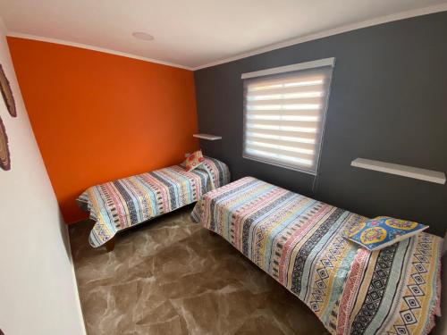 圣佩德罗·德·阿塔卡马Casa Campanario - San Pedro de Atacama, Desconéctate!的橙色墙壁和窗户的客房内的两张床