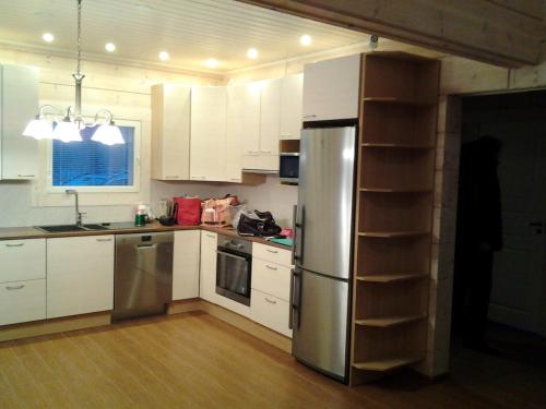 萨翁林纳SaimaanHelmi的厨房配有白色橱柜和不锈钢冰箱