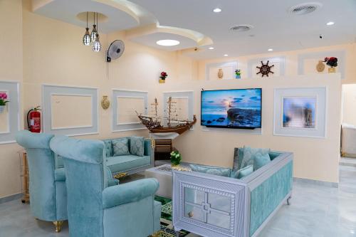 苏尔Arkan Al Barzah Hotel Apartment的客厅配有2把蓝色椅子和电视