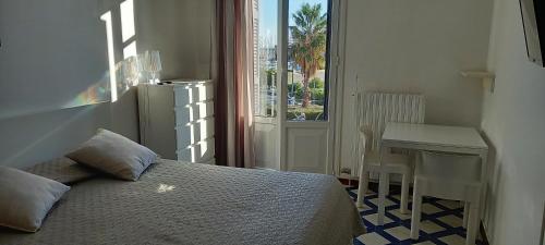 洛阿诺Residence Villa Chiara的一间卧室配有一张床、一张桌子和一个窗户。