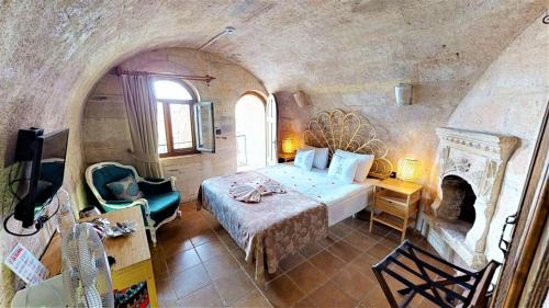 乌奇希萨尔Mimi Cappadocia Luxury Cave Hotel的一间卧室设有一张大床和一个壁炉