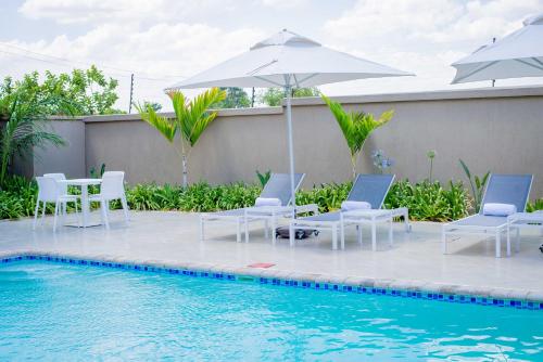 利隆圭Lalibela Boutique Hotel的游泳池旁的游泳池配有椅子和遮阳伞