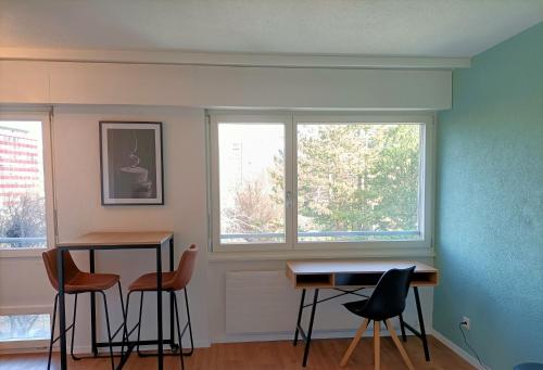 锡永Studio lumineux bien placé en ville de Sion的客房设有桌椅和2扇窗户。