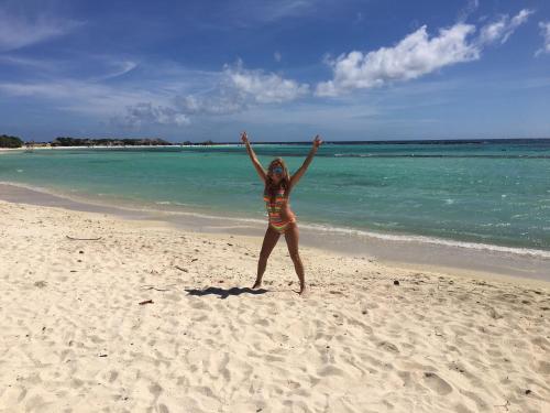 棕榈滩Yoyita Suites Aruba Villa的站在海滩上的女人,手臂在空中
