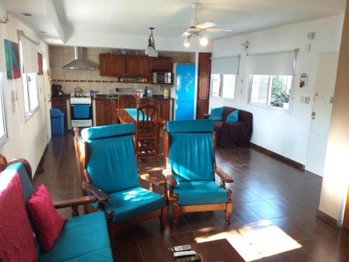 罗尔丹Casa Con Pileta En Roldan的一间带蓝色椅子的客厅和一间厨房