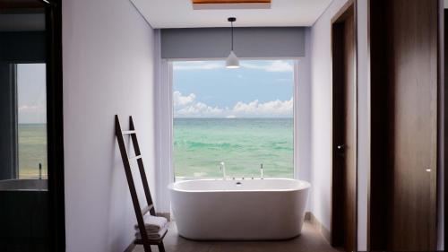 One of A Kind Resort @Trikora Beach - Bintan的带浴缸的浴室和大窗户