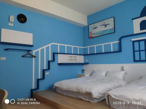后里和和旅宿的一间蓝色的卧室,配有两张床和楼梯