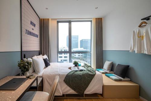 上海上海中建雅诗阁lyf酒店(虹桥机场国家会展中心店)的一间卧室配有一张床、一张书桌和一个窗户。