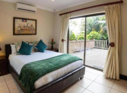 KelsoMarula Mews T17 Villa - Selborne Golf Estate的一间卧室设有一张床和一个滑动玻璃门